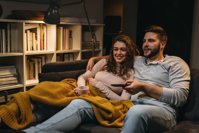 A couple sitting on a couch watching TV.