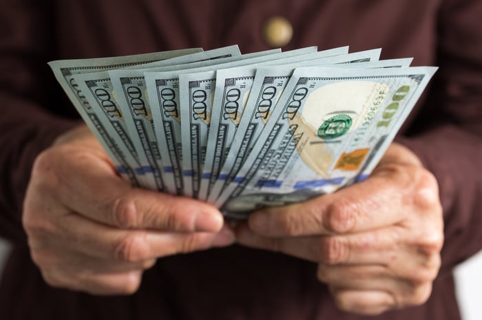 A person holding a fan-line spread of $100 bills.