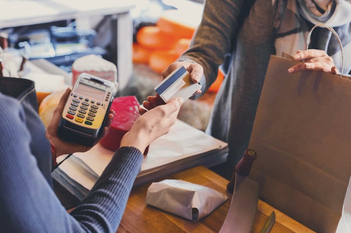 A person makes a credit card payment at a store checkout.