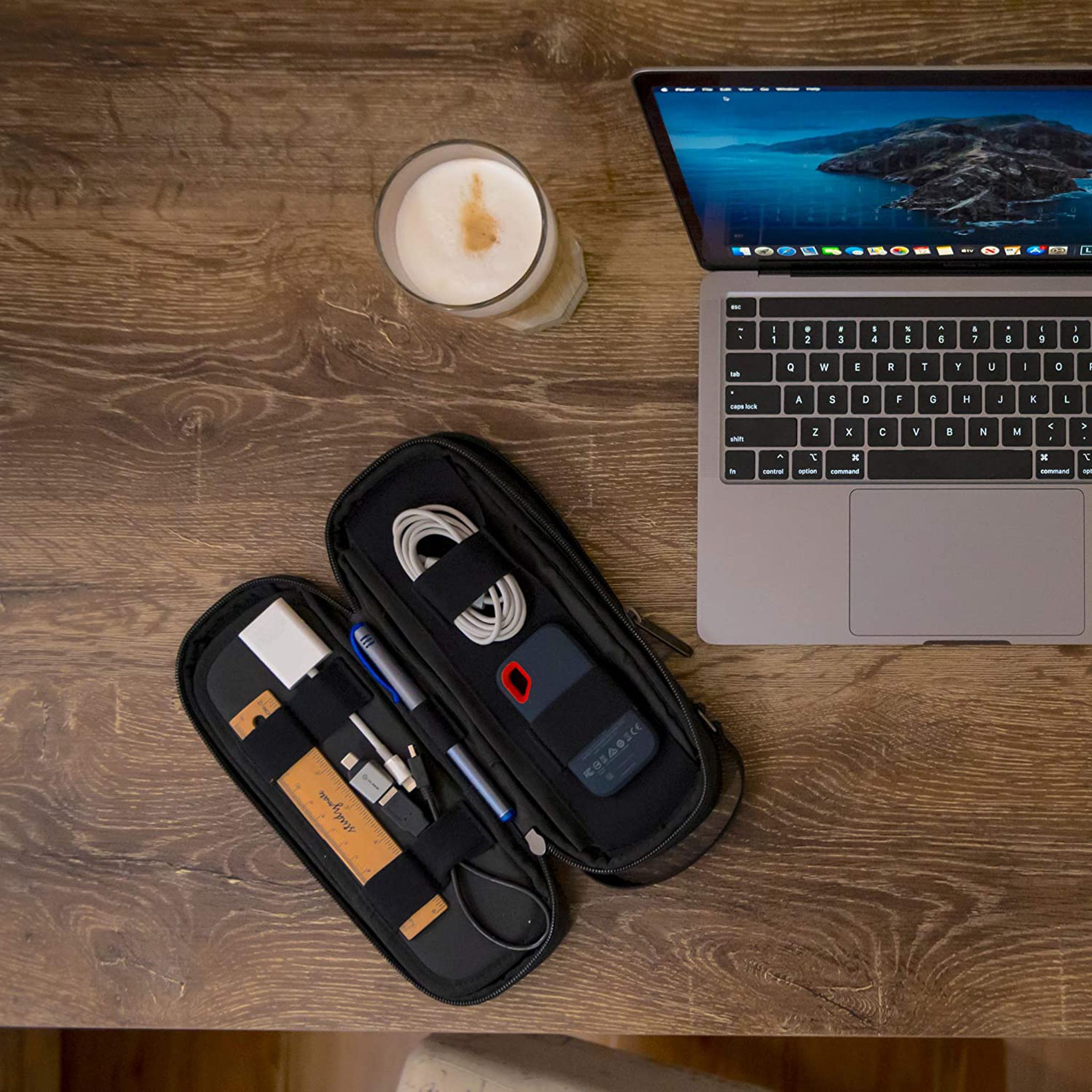 Open gadget bag filled with cords and other miscellany next to a candle and a laptop.