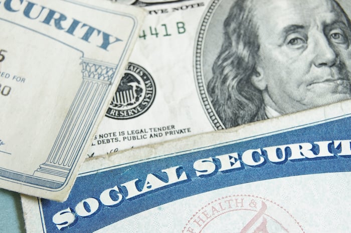 A Social Security card laid on top of a $100 bill.