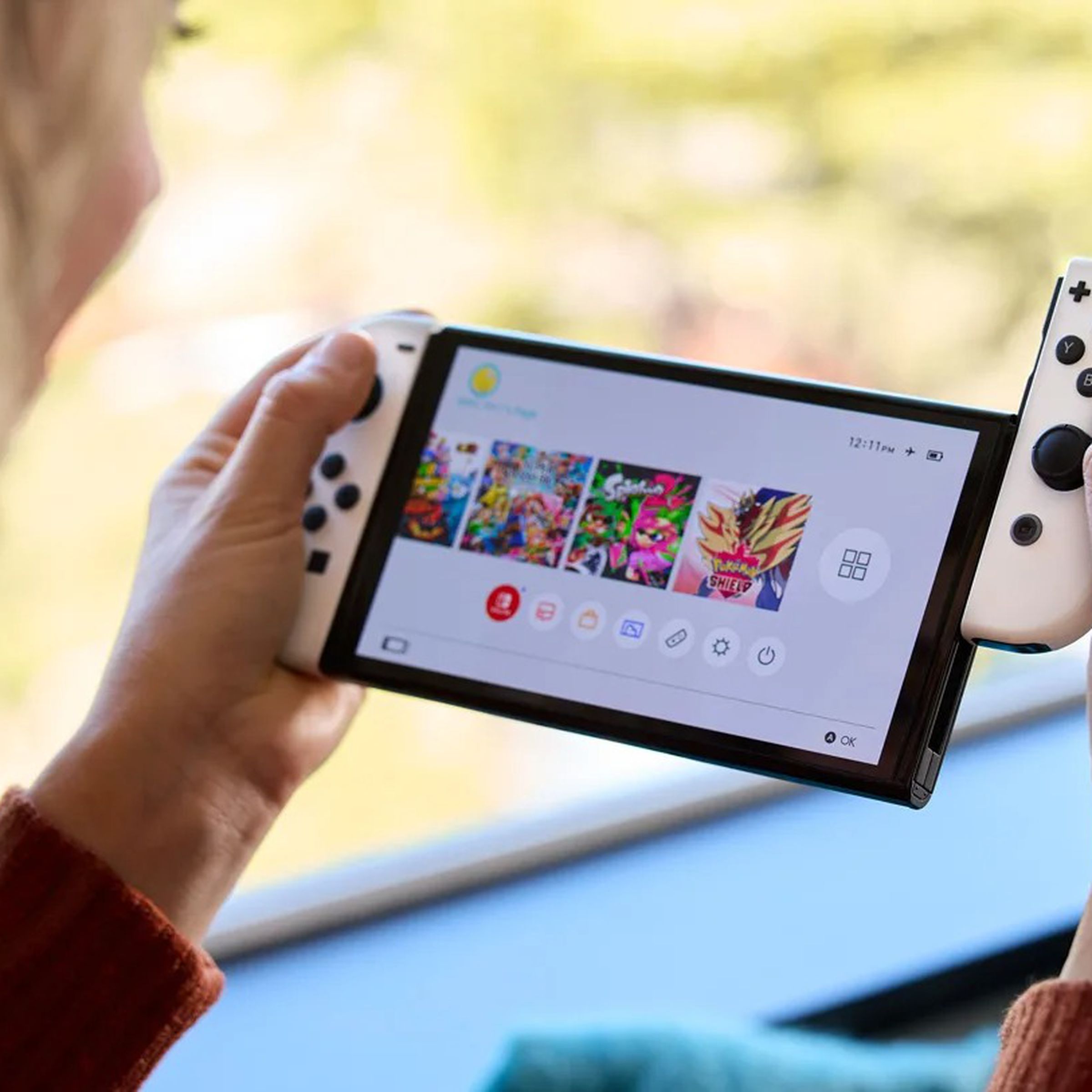 A close-up image of a woman sliding a Joy-Con controller off a white Nintendo Switch OLED.