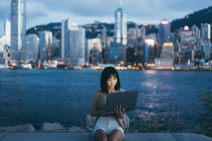 A woman looking at a laptop in front of a skyline